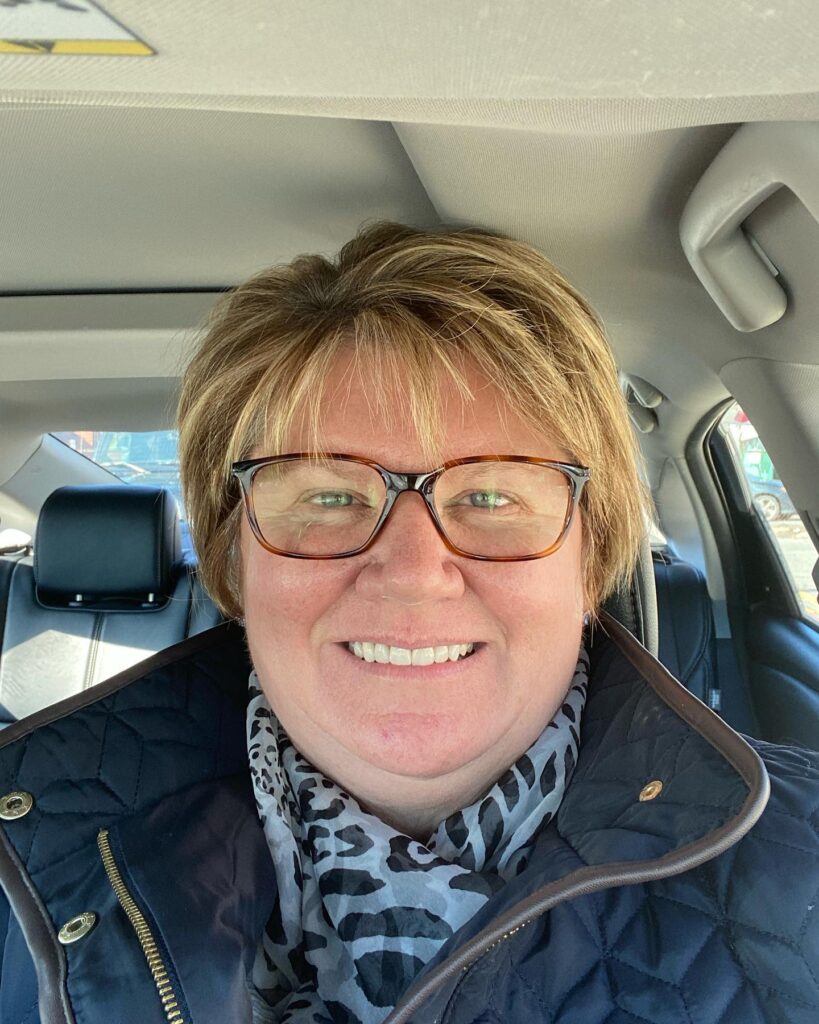 A woman with a golden blonde layered pixie cut featuring wispy bangs and light texture.