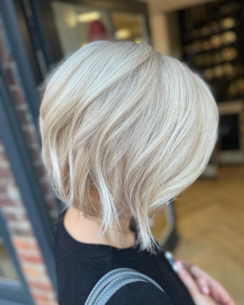 A woman with a straight icy platinum bob featuring wispy layers and textured ends.