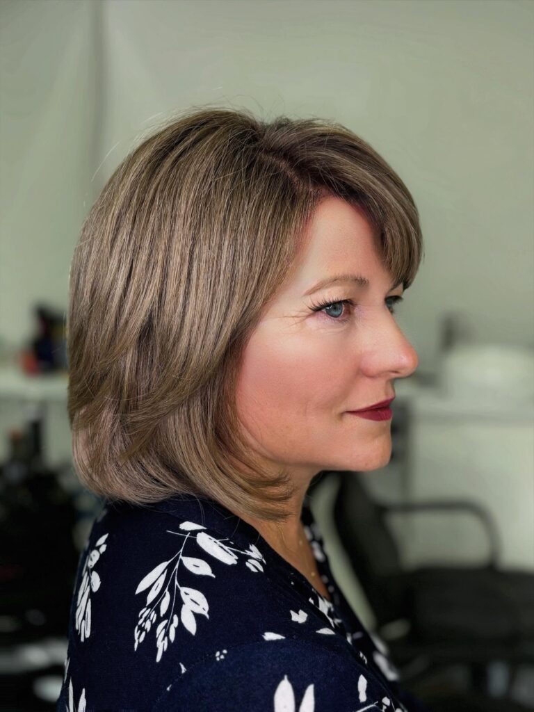 A woman with a square face shape wears a bright pearl blonde textured pixie cut with short layered sides.