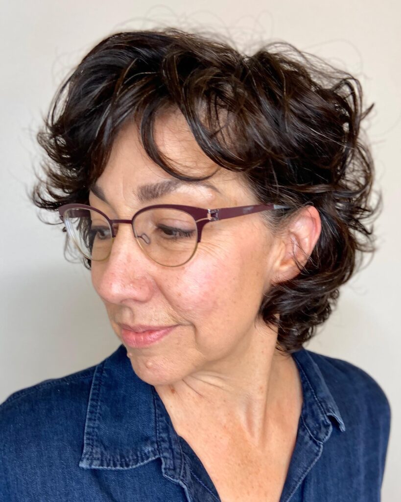A woman with a chin length pearly white bob featuring soft wavy layers and a feathered finish.