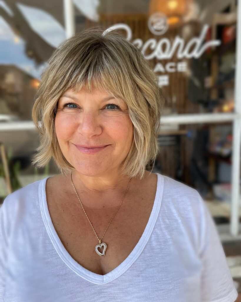 A woman with a textured ash blonde bob featuring choppy layers and a piecey fringe.