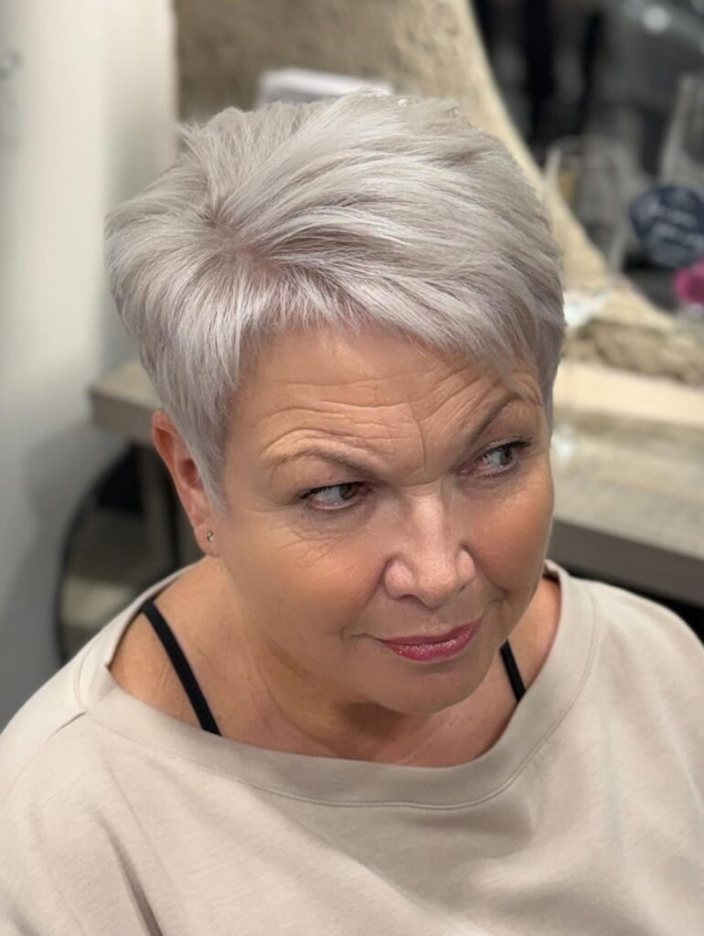 A woman with a short silver and white pixie cut featuring voluminous textured layers styled upward.
