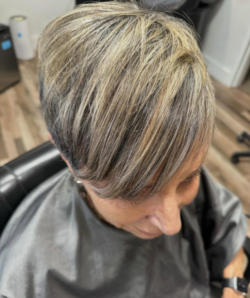 Overhead shot of an older woman with a chic short icy blonde and grey pixie haircut.