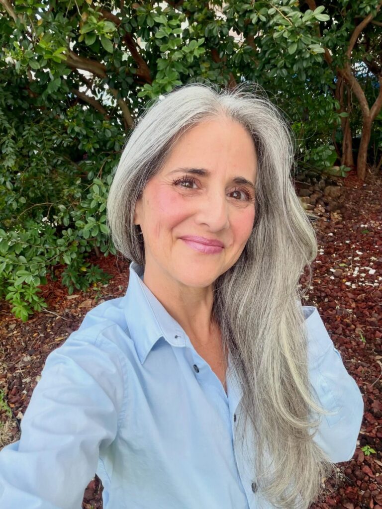 A woman with very long layered silver hair parted in the middle and flowing over her shoulders.