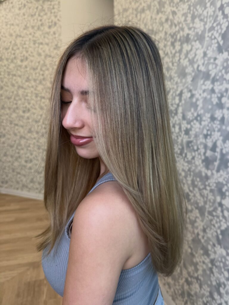 A young woman with smooth straight medium long hair showing off her cool ash blonde highlights.