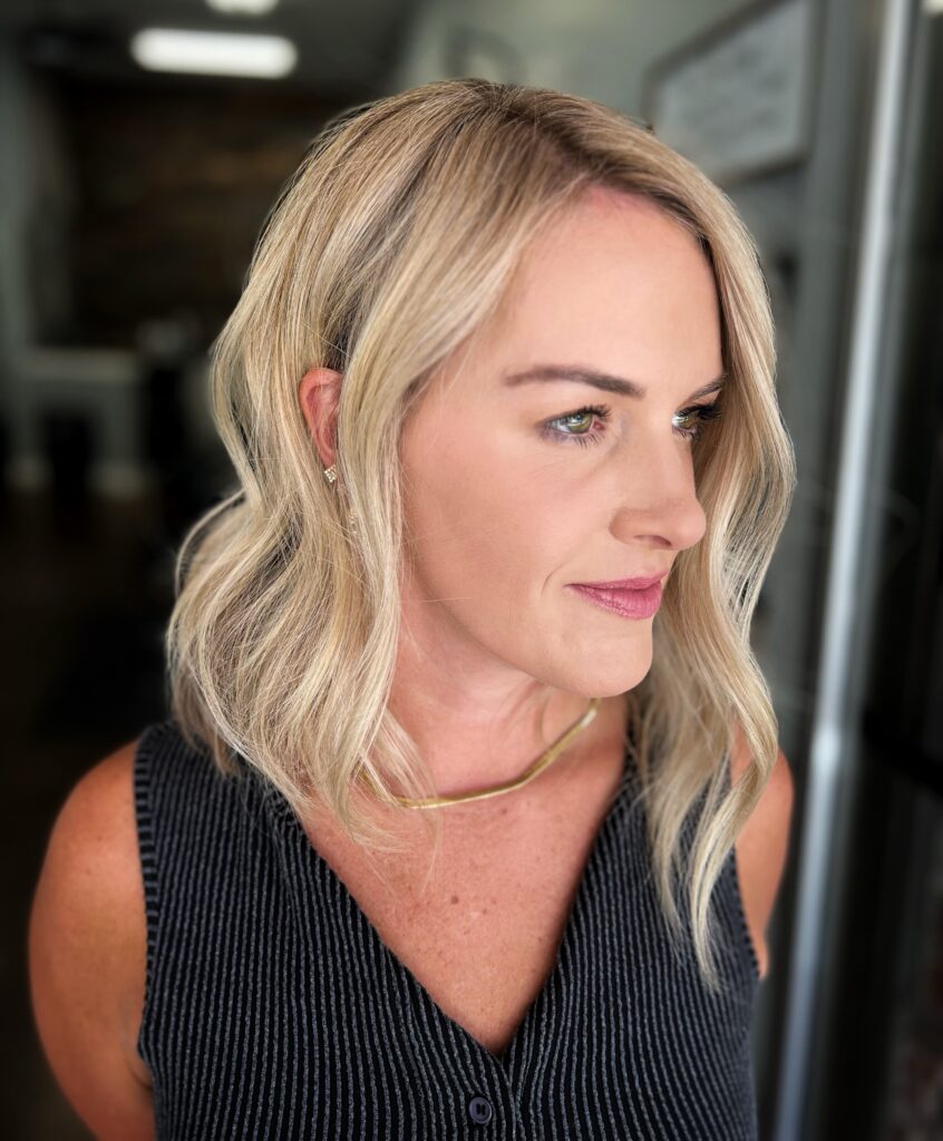 A woman with a textured blonde bob styled with soft undone waves shows off her dimensional hair color and face framing layers.