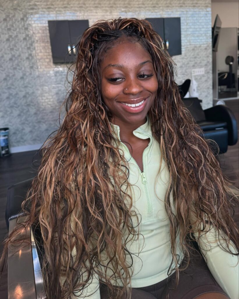 Long wavy hair with a braided crown and caramel highlights flowing past the shoulders.