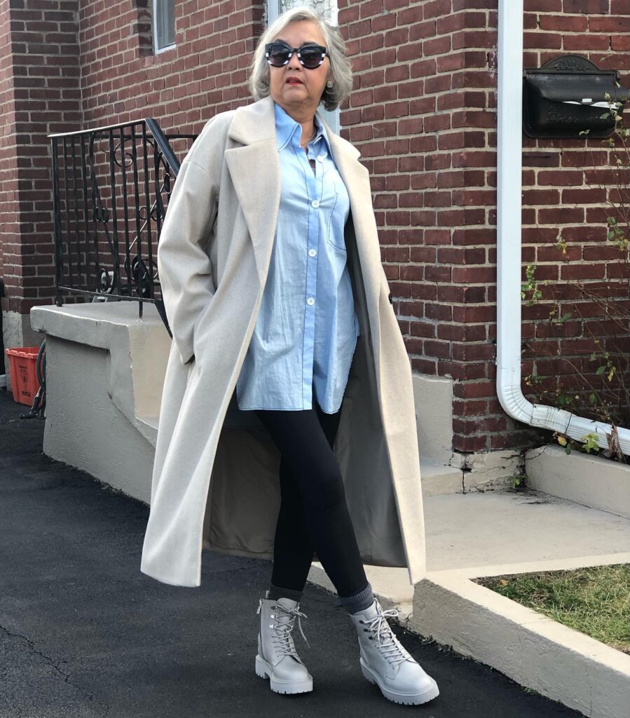 A woman wearing sunglasses with a voluminous chin length grey bob styled with a deep side part and soft waves.
