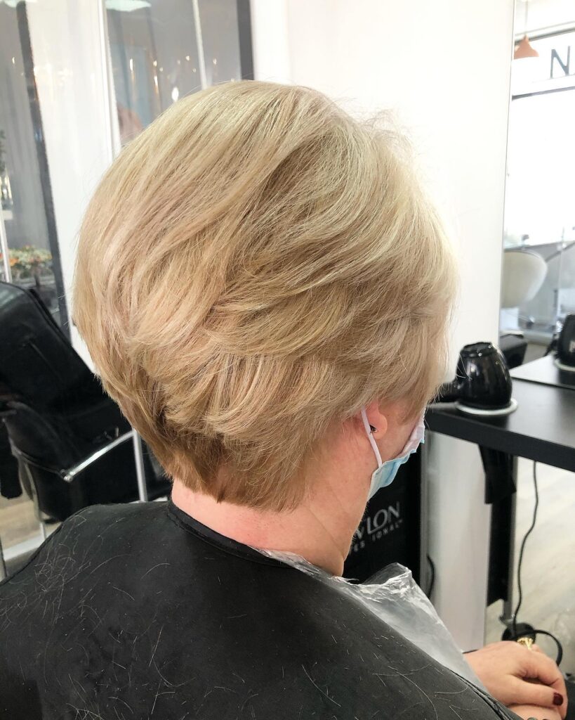 A side profile view of a woman with a layered copper red shag haircut featuring a full fringe and choppy texture.