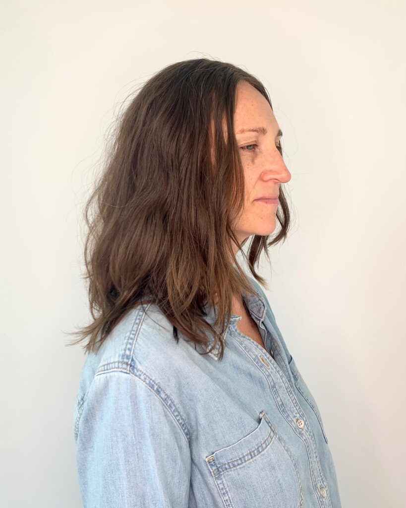 A side profile view of a woman with a heavily layered shoulder length ice blonde shag haircut.