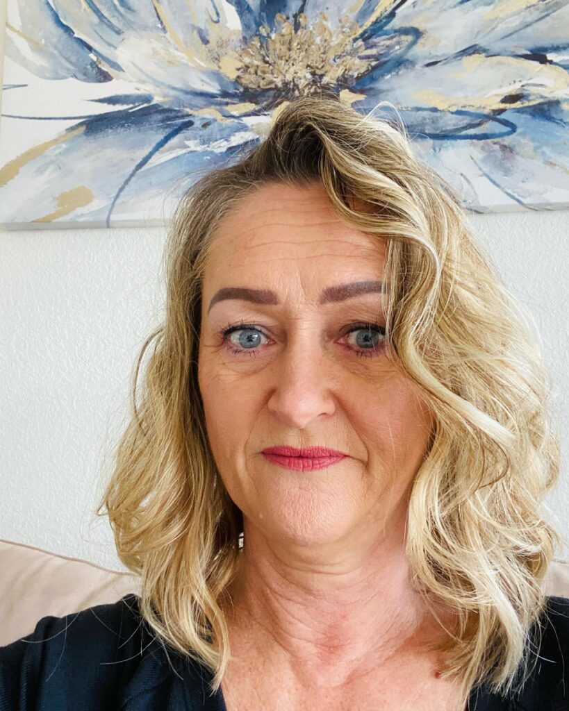 A woman with a shoulder-length golden blonde hairstyle featuring a deep side part, voluminous roots, and soft waves.