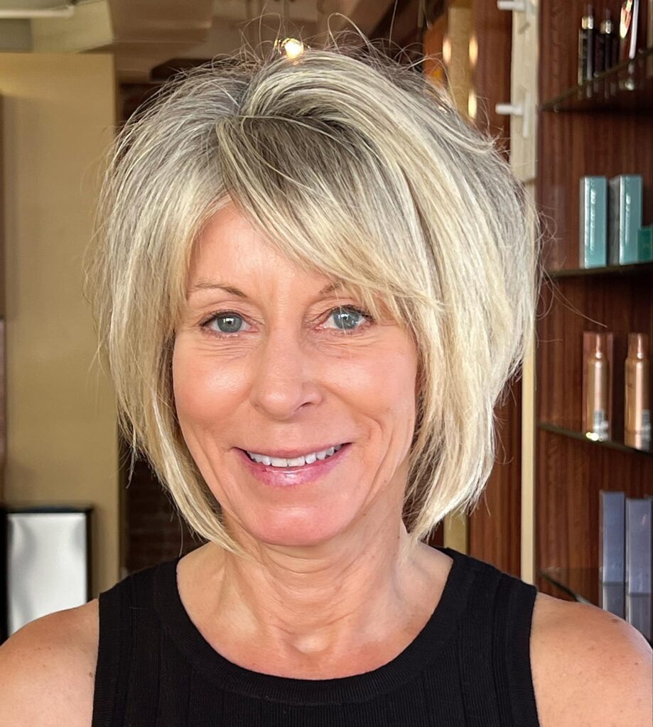 A woman with fine hair showcases a voluminous jaw-length platinum blonde bob with short crown layers and a side-swept fringe.