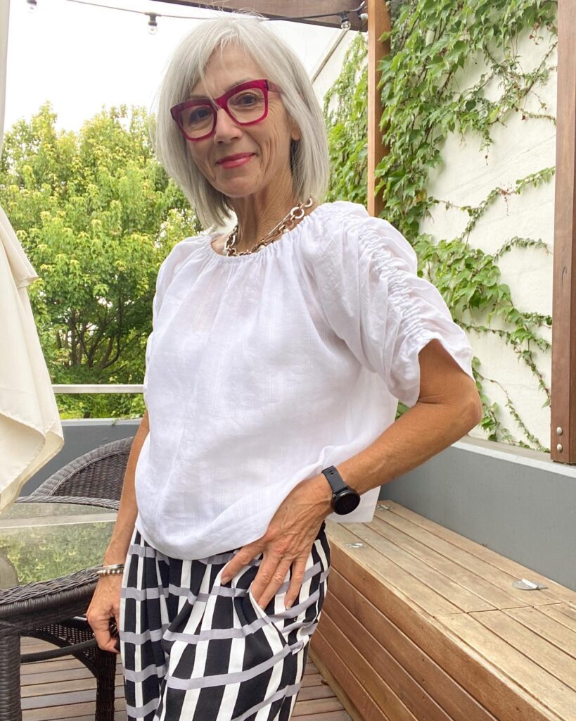 A smiling woman over 60 with a straight silver chin-length bob hairstyle and side-swept bangs.