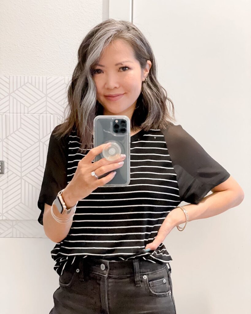 A woman with a wavy shoulder length bob haircut showing blended dark hair with natural silver grey highlights.