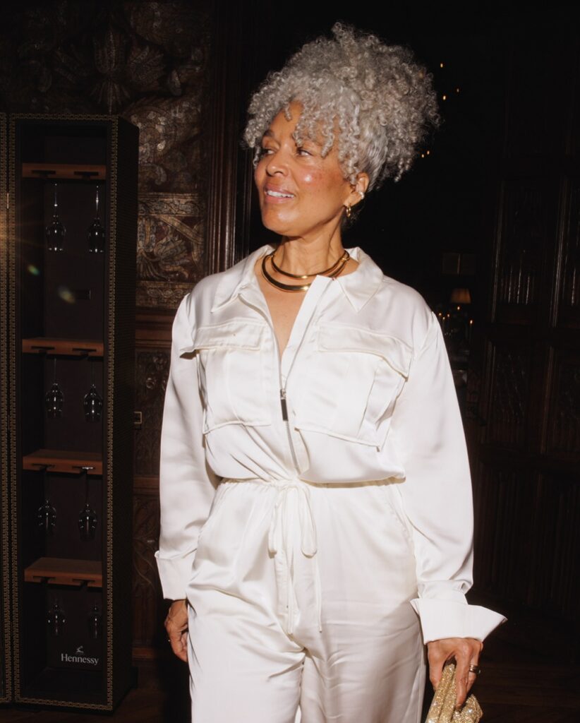 A woman wearing a glamorous high updo featuring a voluminous crown of tight silver curls.