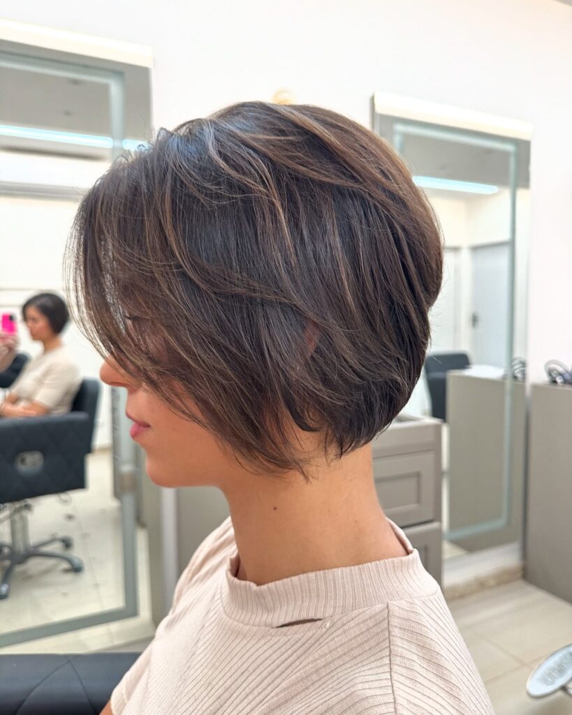 A side profile view of a woman with a straight, stacked jaw-length espresso brown bob featuring soft side-swept layers.