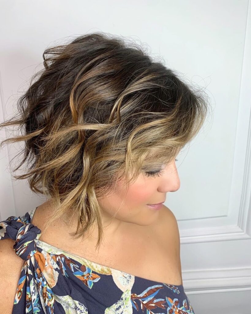 A woman in side profile showcases a messy, layered brunette bob with warm honey highlights and textured waves.