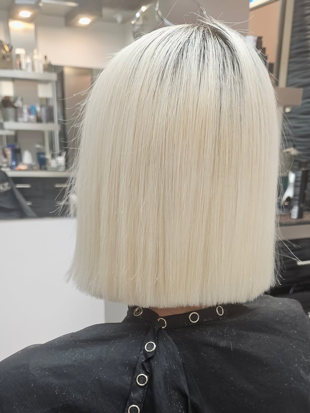 Chin-length platinum blonde blunt bob with a sharp, even cut and sleek straight finish for a clean modern look.