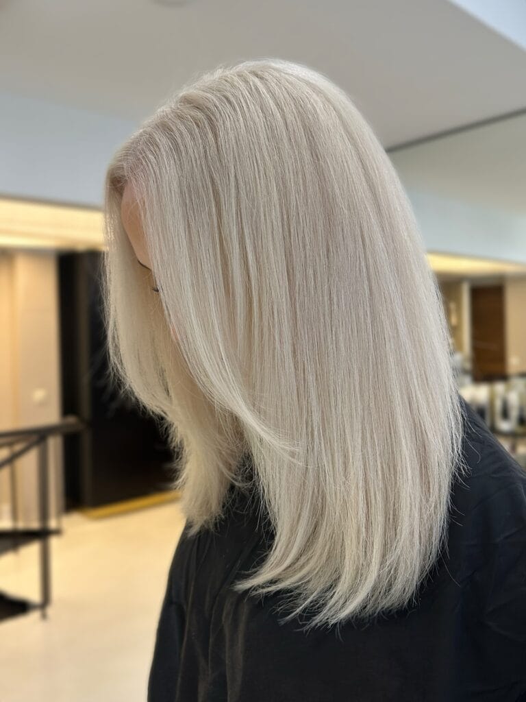 Sleek shoulder-length straight haircut with soft layers and cool platinum blonde color, styled smooth with a subtle inward curve at the ends for a polished, modern look.