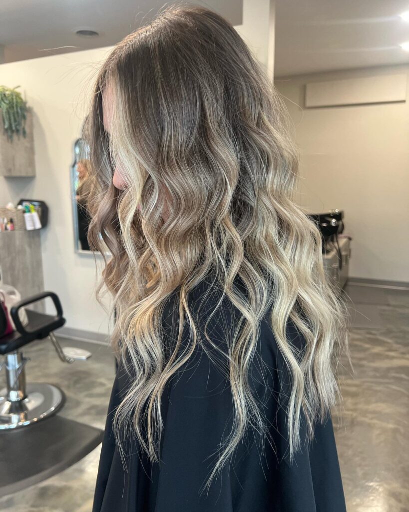 A woman with medium length wavy hair in a lived in sandy blonde color.