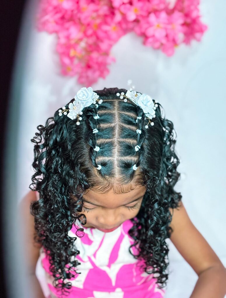 Rubber band hairstyle with middle part sections and defined curls decorated with hair accessories.