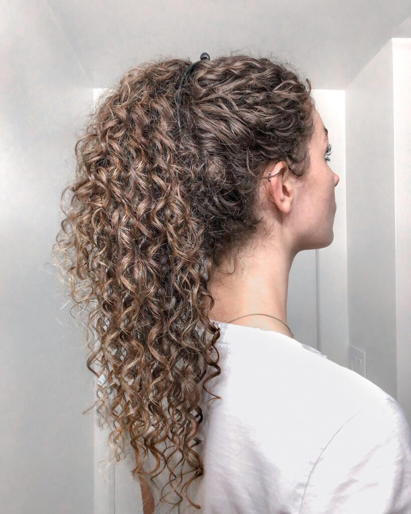 Long naturally curly hair styled in a high voluminous ponytail with defined textured curls.