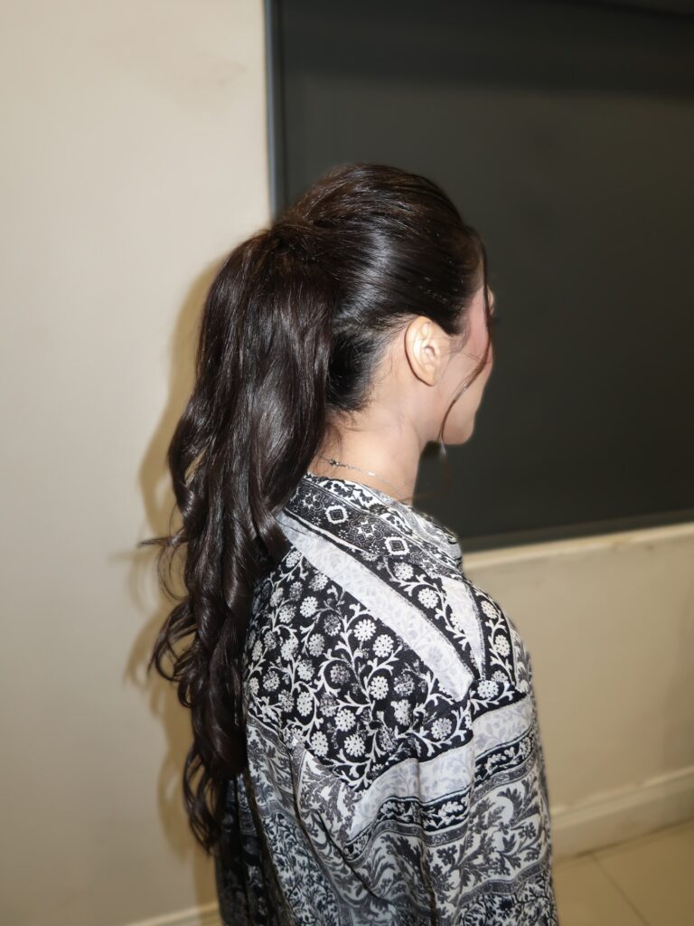 Long dark hair styled in a high ponytail with soft loose waves and a smooth crown.
