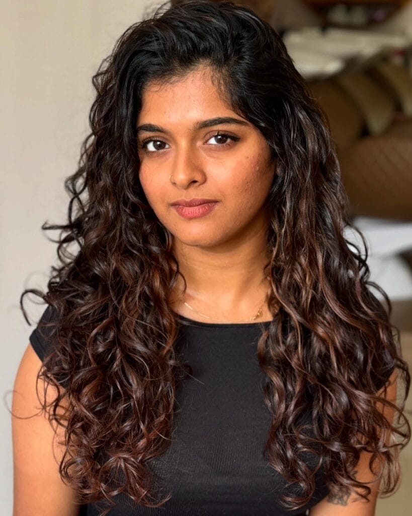 Long layered curly hairstyle with soft natural flow and loose curls.