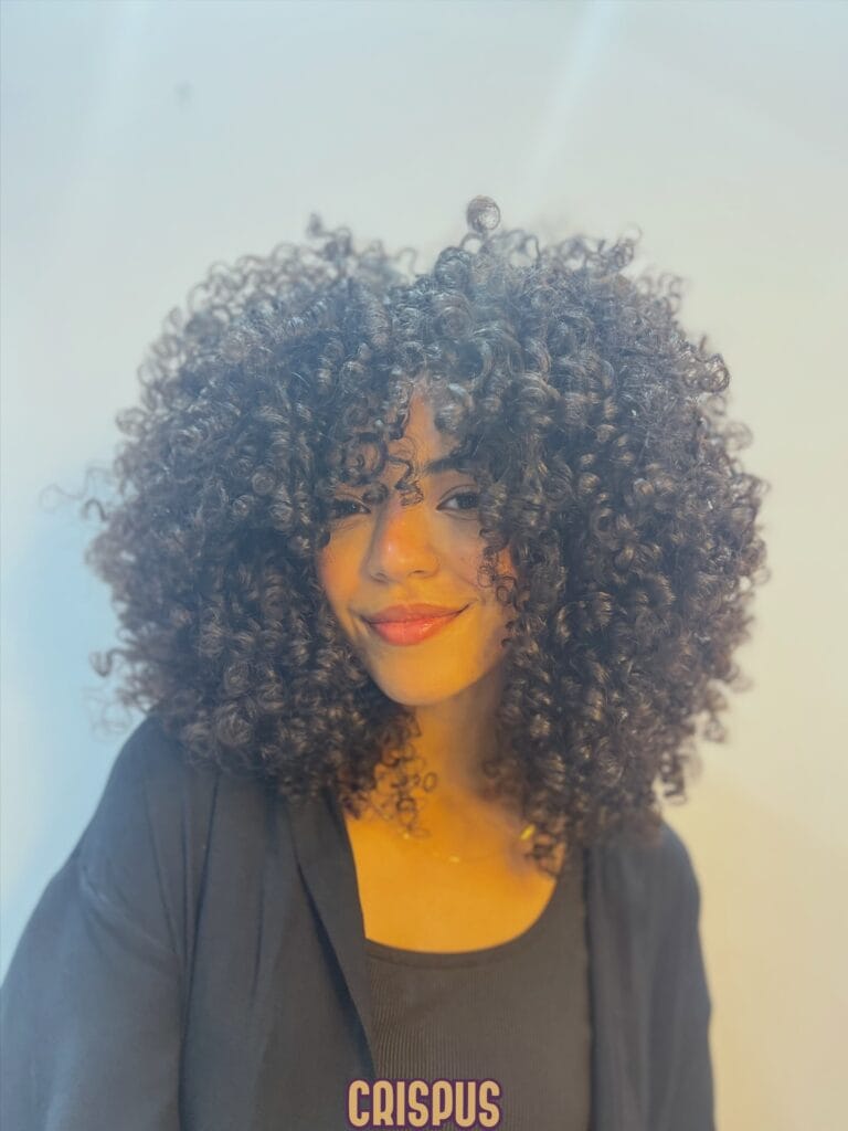 Rounded curly hairstyle with tight curls and full balanced volume.