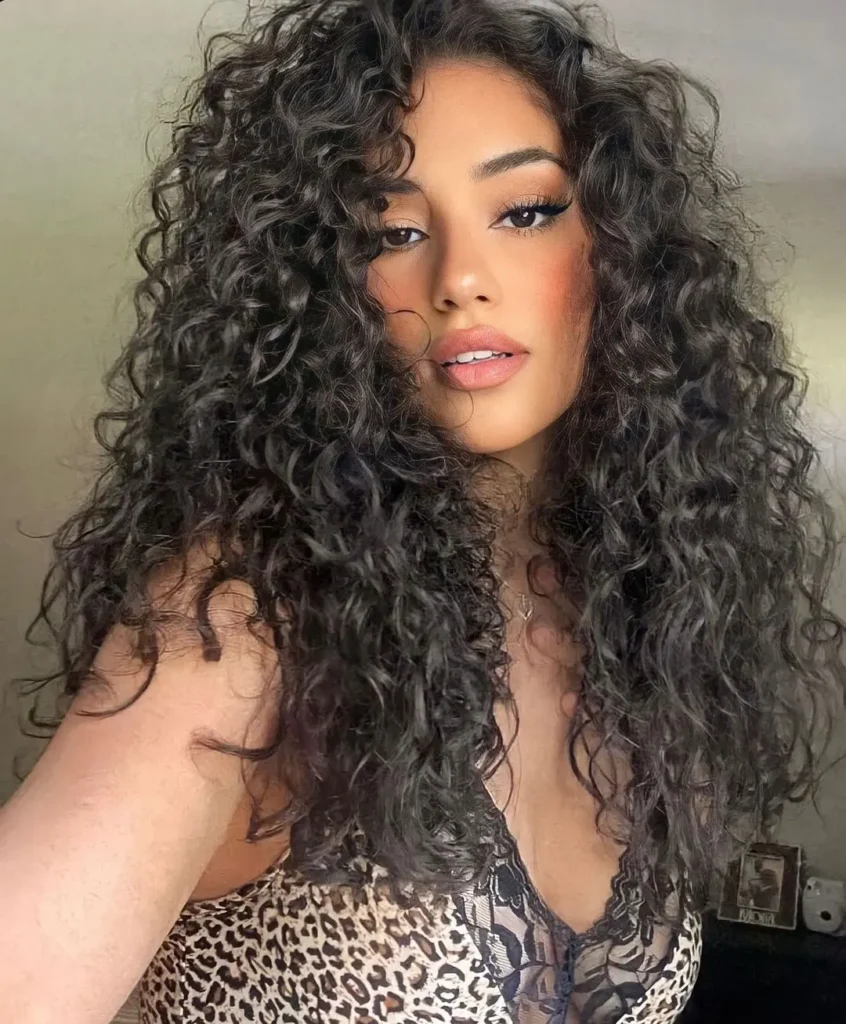 Long curly hair with defined curls and natural volume throughout.