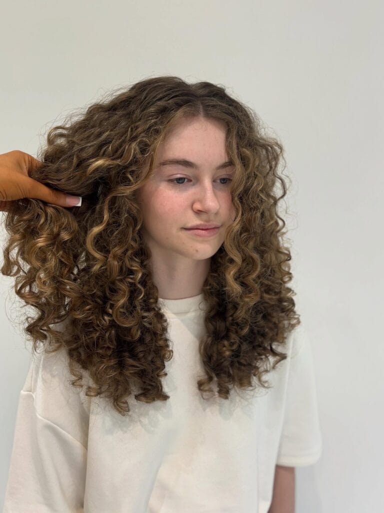 Long curly hairstyle with soft layers and loose natural texture.