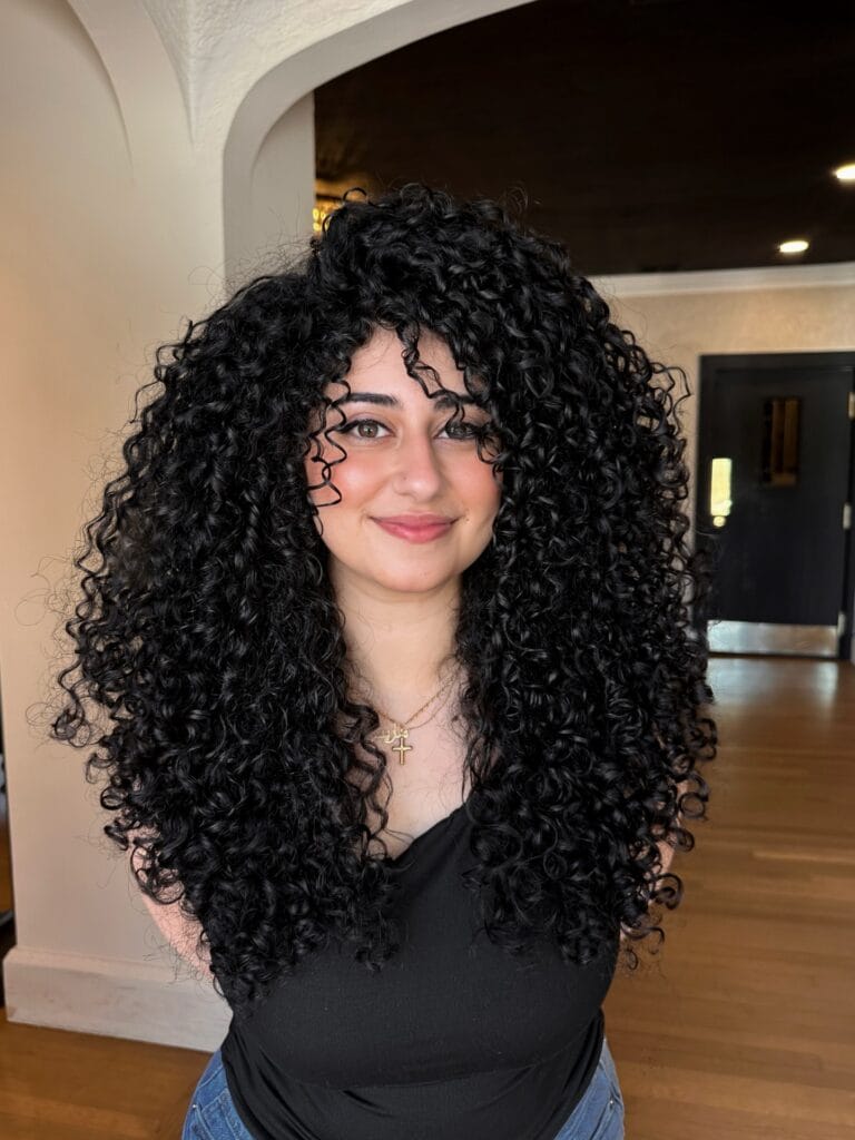 Long curly hairstyle with tight defined curls and full layered volume.