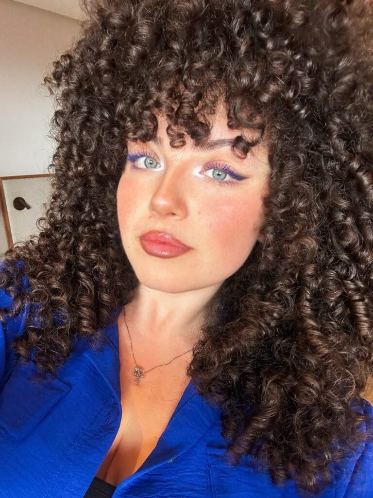 Curly haircut with tight curls and a full textured fringe.