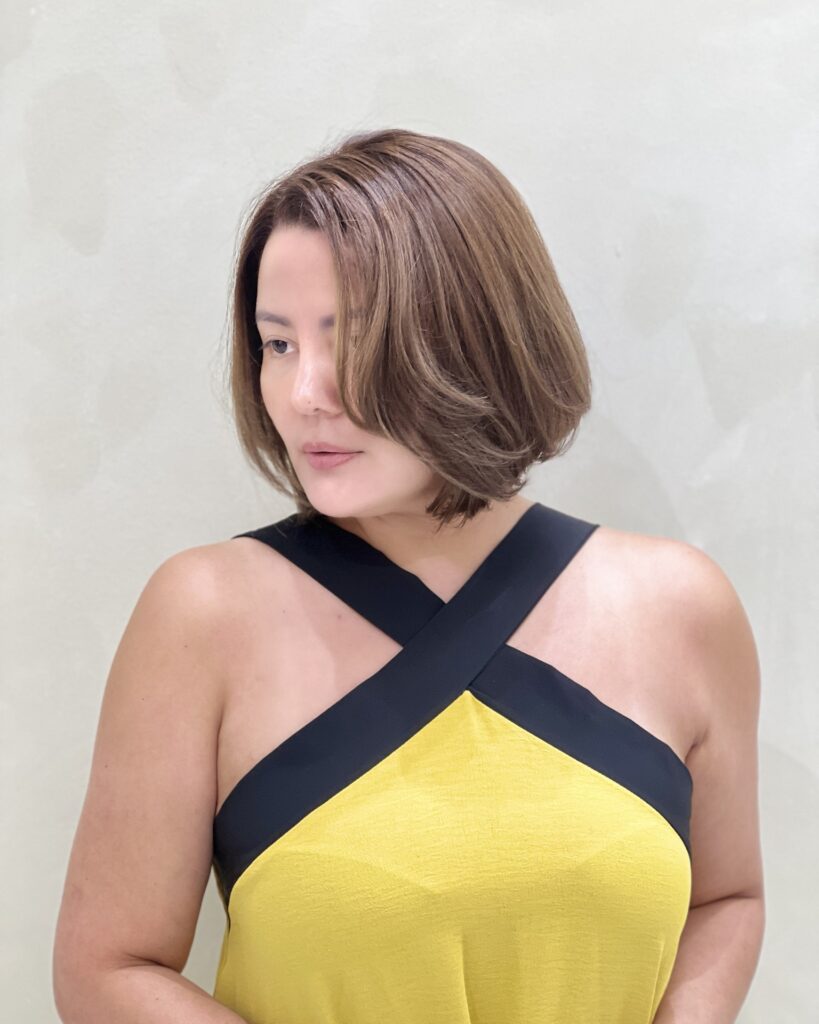 Short rounded bob with a side part and soft brown layers.
