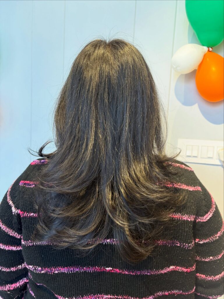 The back view of a woman with medium-length dark brown hair cut into a U-shape with layered, flicked-out ends.