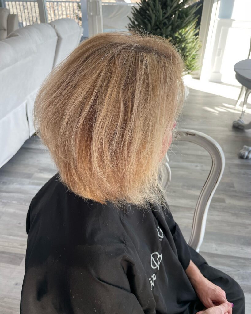 A side view of a woman with a golden blonde bob featuring soft layers and a voluminous, rounded shape.