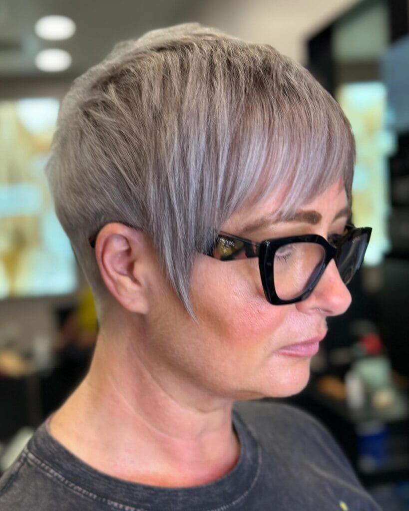 Short blonde pixie cut with tapered layers and soft volume at the crown.