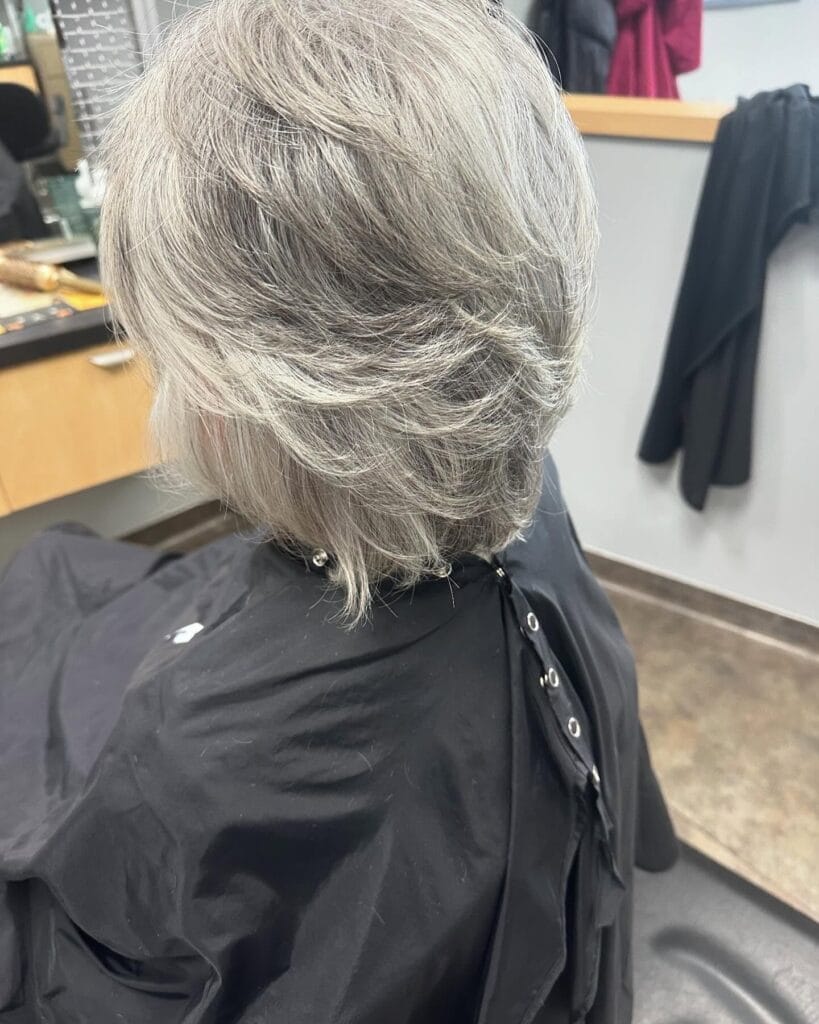 Short to medium gray layered bob with soft volume and feathered texture.