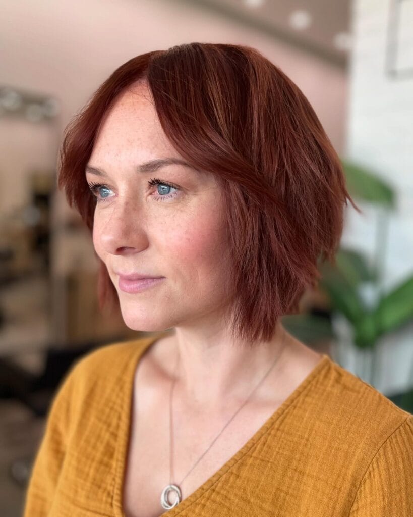 Short red layered bob with a side part and soft waves.