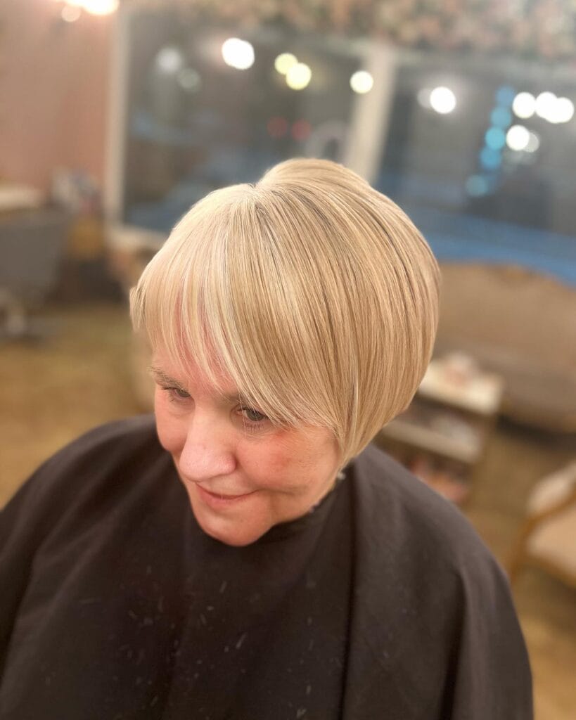 Short blonde bob with soft layers and feathered bangs.