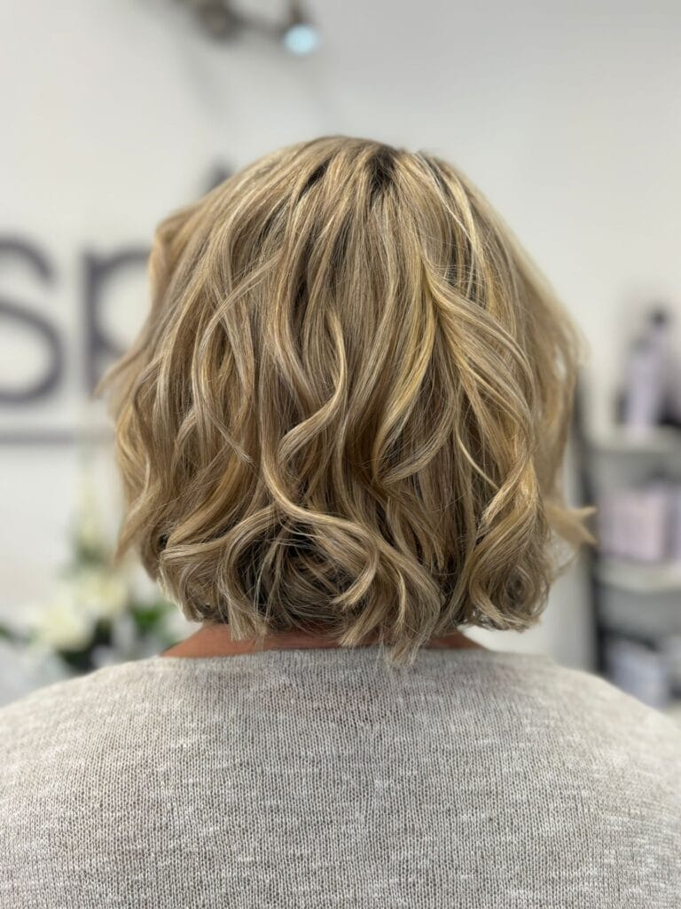 Short curly bob with soft layers and warm blonde tones.