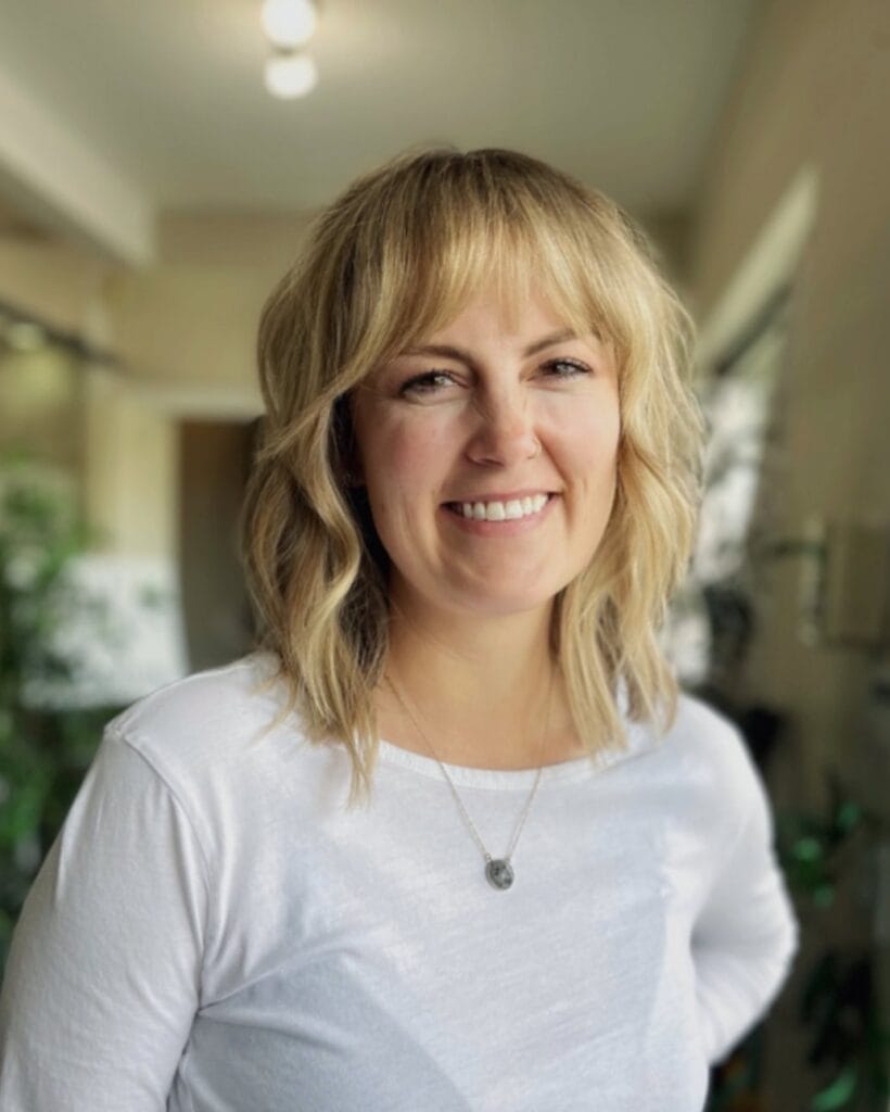Shoulder length wavy bob with wispy fringe and soft blonde tones.