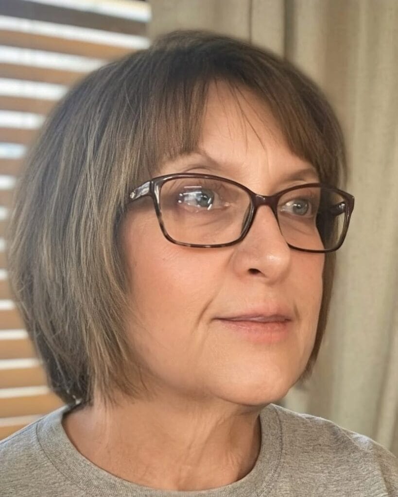 Rounded bob with soft full fringe and natural brown color.