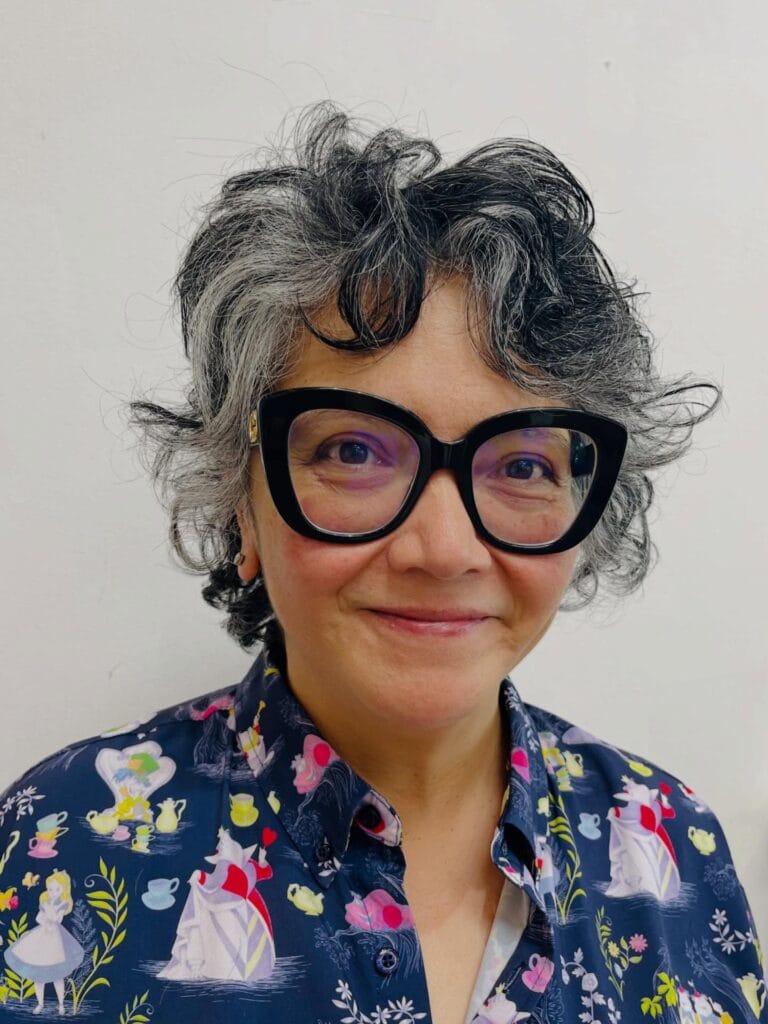 Short curly pixie bob with soft fringe and natural gray texture.