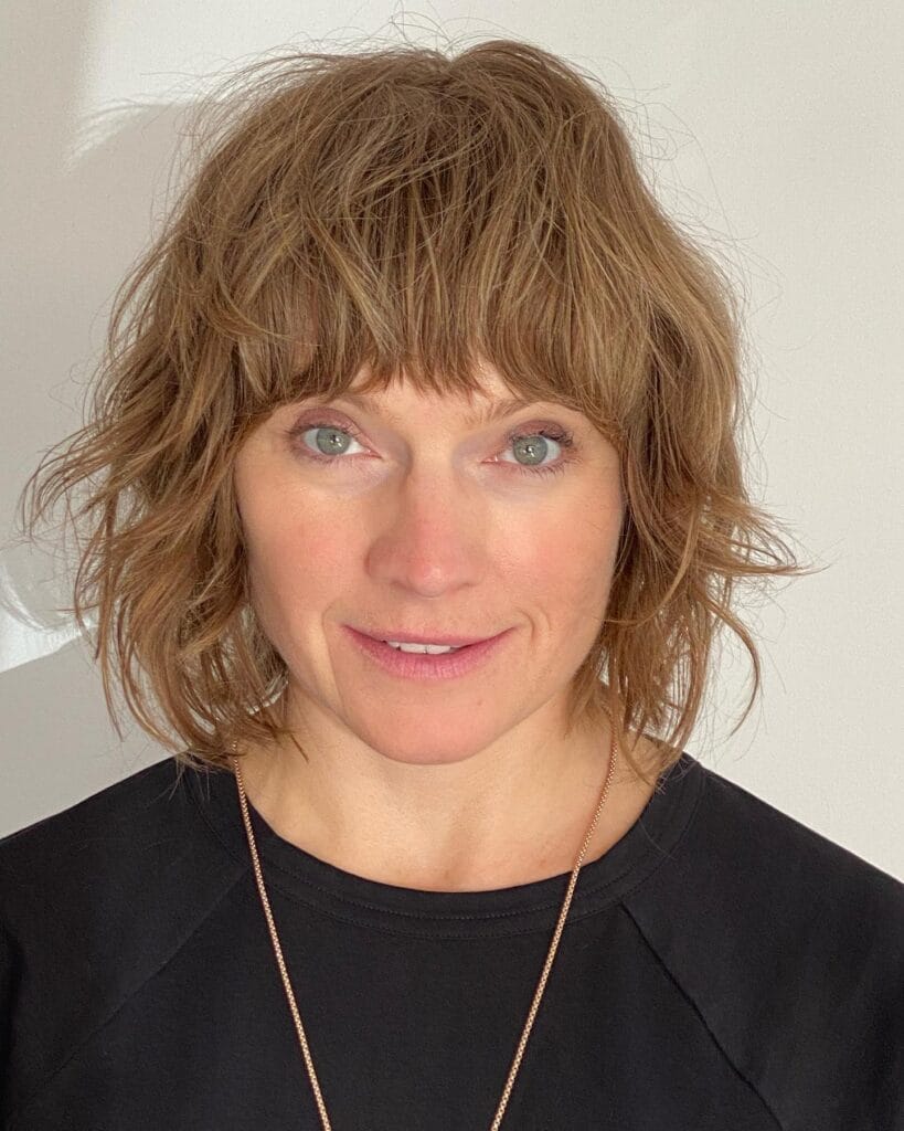 Short shaggy bob with choppy layers and wispy fringe in light brown tone.