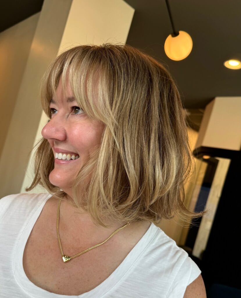Shoulder length bob with soft layers and wispy fringe in blonde tones.