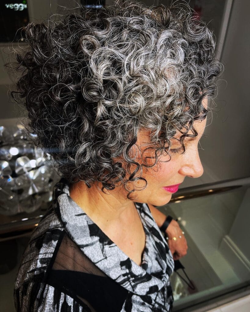 Short curly gray bob with tight defined ringlets and natural volume around the face.