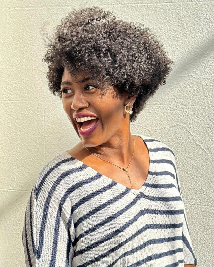 Voluminous gray curly bob with soft bangs and rounded shape.