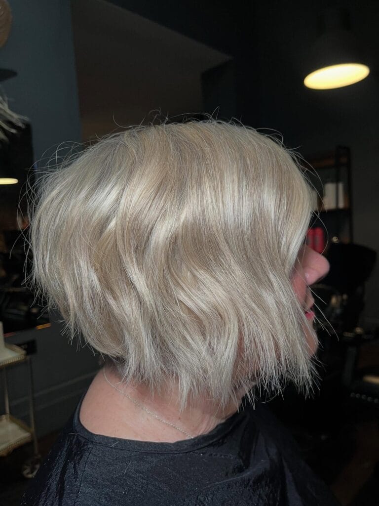 Textured blonde gray bob with wispy bangs and soft layers.