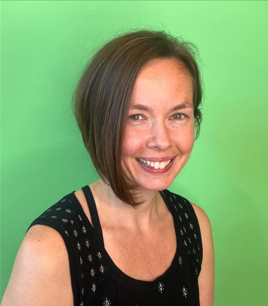 Short blonde inverted bob with stacked layers at the back and longer face-framing front pieces.